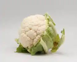 Fresh ZabhiaNow cauliflower head with green leaves, showcasing its white, compact, and healthy appearance.